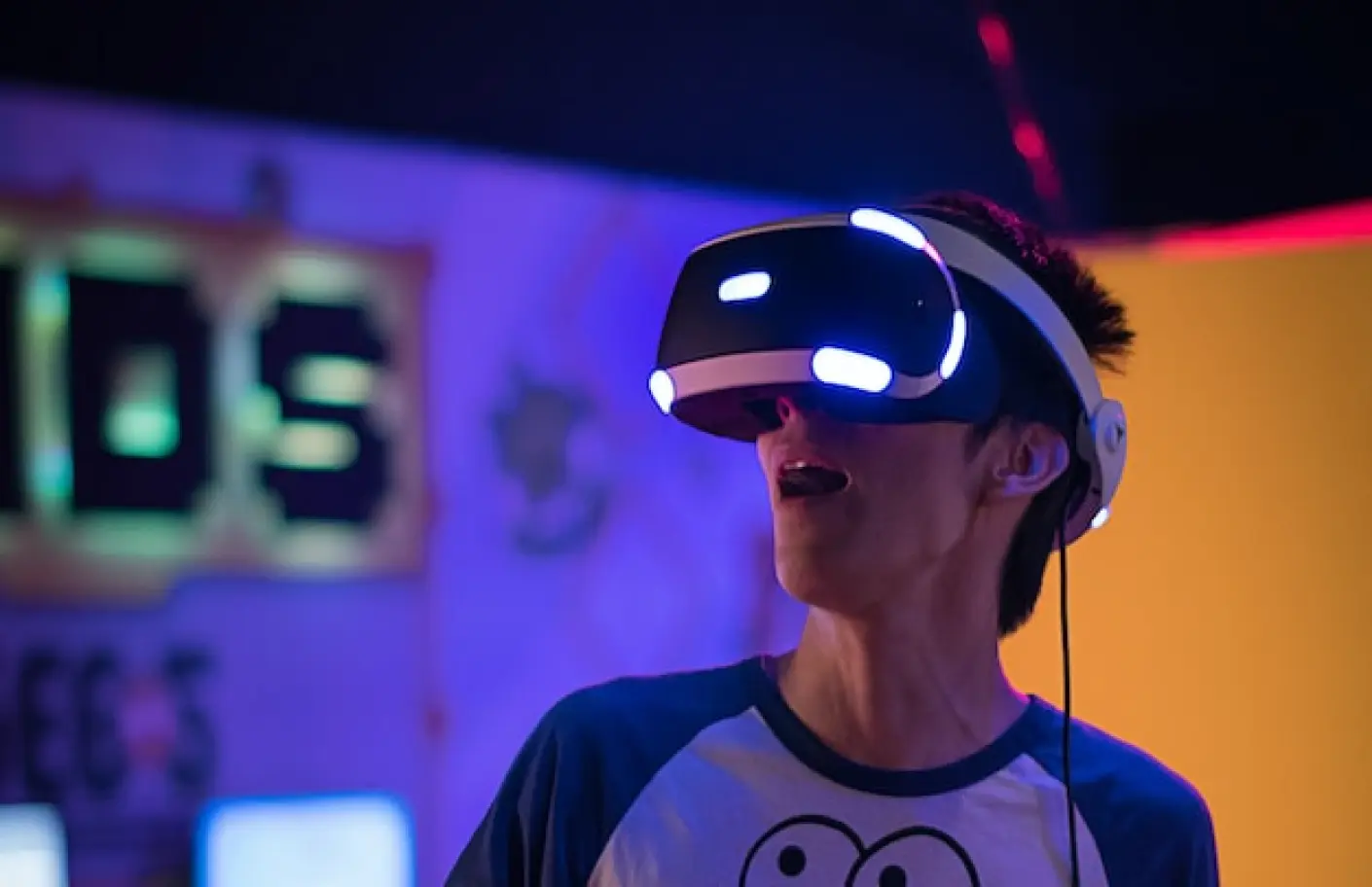 A person wearing virtual reality goggles in a room of neo lights implies the latest technologies